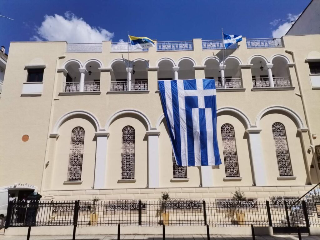 Το κτίριο του Προκοπείου Πολυδύναμου Εκκλησιαστικού Κέντρου με ελληνικές σημαίες